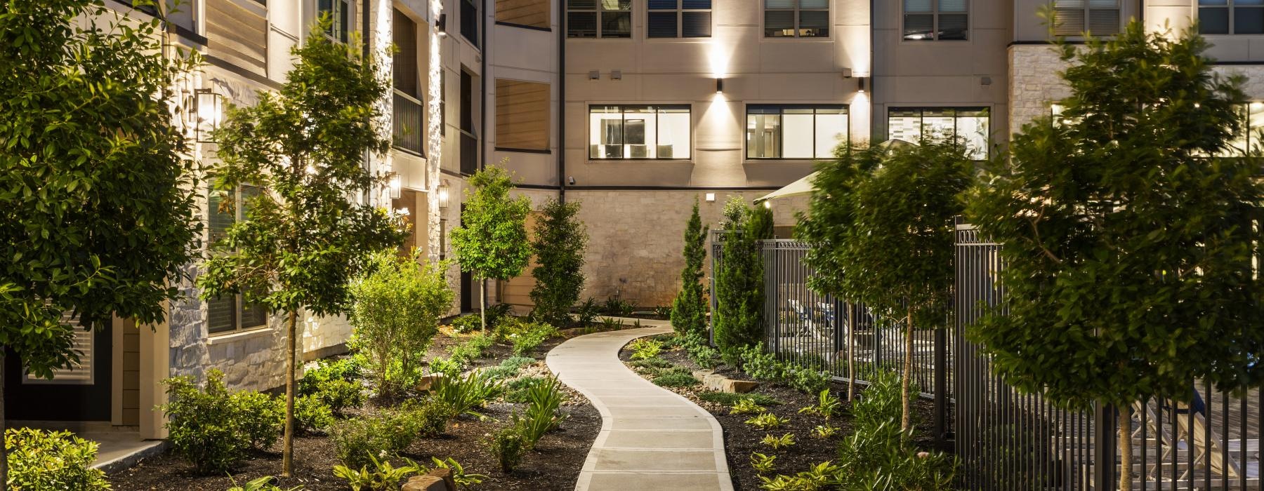 a courtyard with trees and plants in front of a building